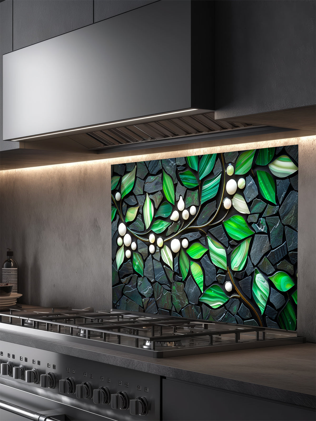 Tempered glass kitchen backsplash featuring a highly realistic 3D illusion of a stone mosaic showcasing vibrant emerald green agate-like leaves and white pearl berries on a glowing golden branch against a dark charcoal stone background, installed behind a modern black stove.