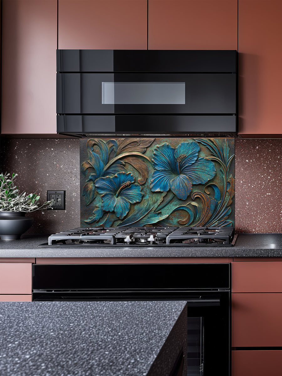 Tempered glass kitchen backsplash featuring a highly realistic 3D faux metal relief design of large tropical hibiscus flowers with a rich teal patina and antique copper accents over a dark textured background, installed behind a modern stainless steel stove.