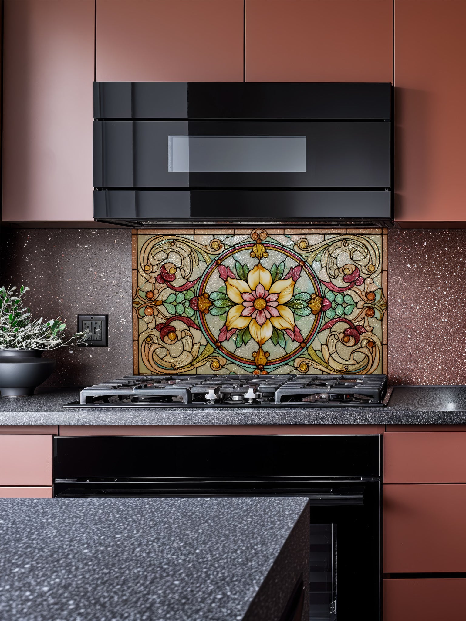 a kitchen with a large, colorful stained glass tile backsplash above the stovetop. The backsplash has a floral design with yellow and green elements. The kitchen has pink cabinets and a black oven, creating a modern and stylish aesthetic.