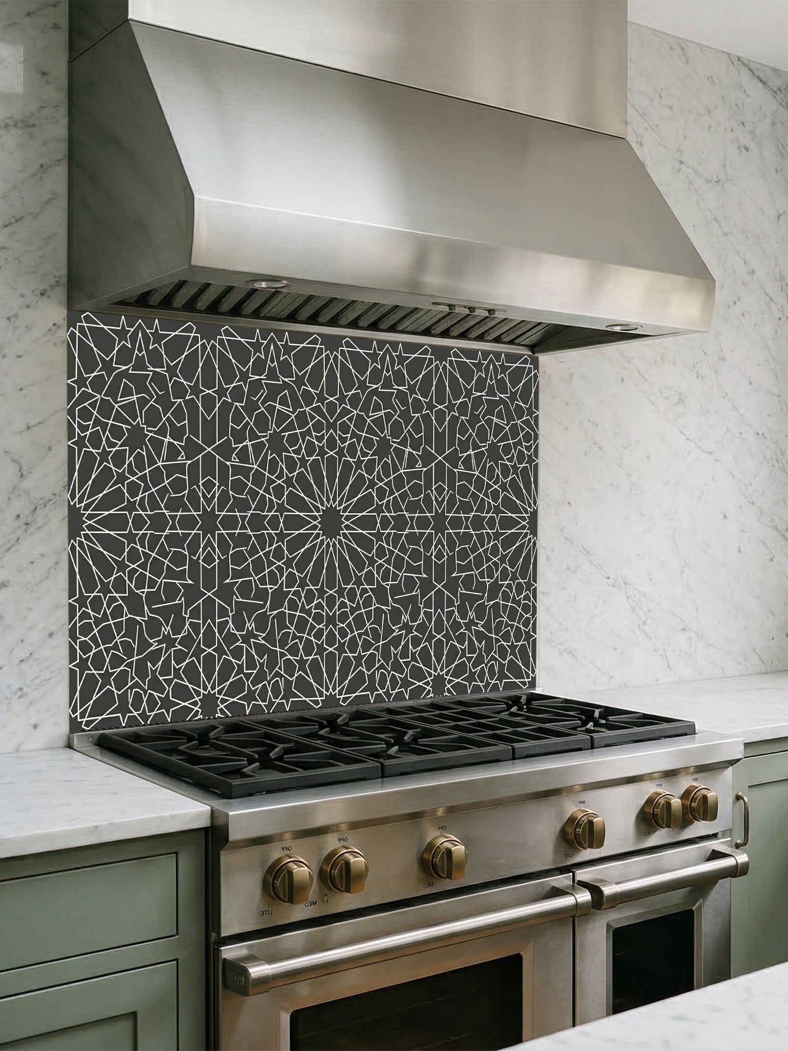 Stainless steel range hood above a gas stove with decorative tile backsplash.