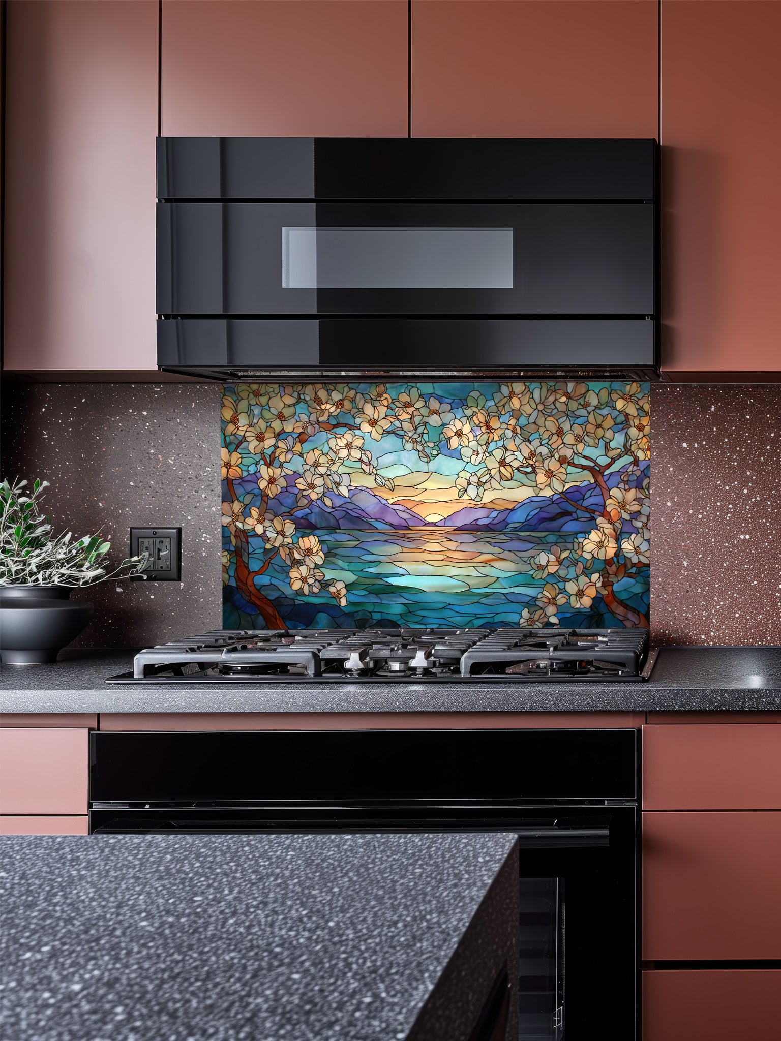 A modern kitchen featuring a tempered glass backsplash with a beautiful stained glass effect landscape, showing blooming trees, a mountain lake, and a sunset, installed behind a stainless steel stove.