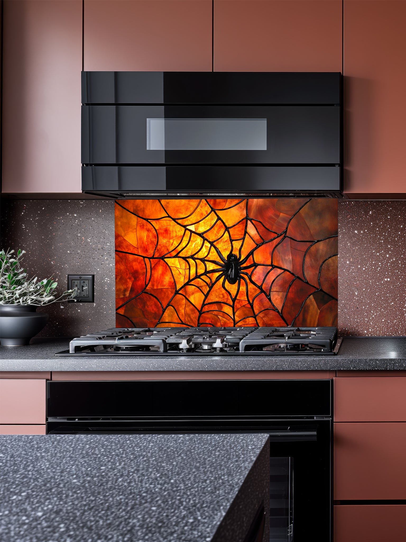 Tempered glass kitchen backsplash featuring a highly realistic 3D illusion of stained glass art showing a black spider in the center of a glowing amber and orange spider web, installed behind a modern black stove.