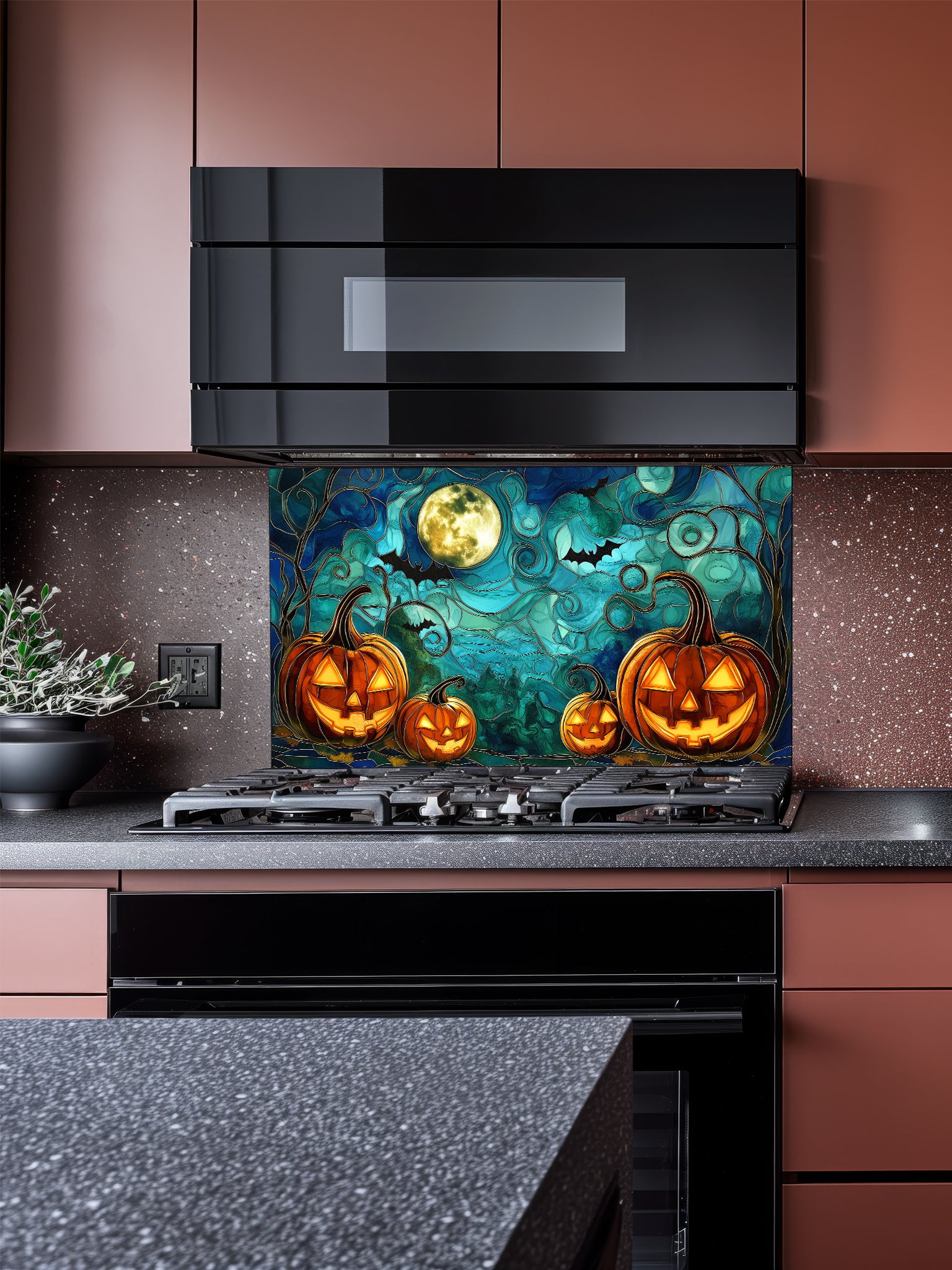 A festive kitchen featuring a tempered glass backsplash with a spooky stained glass effect illustration showing glowing Halloween pumpkins, bats, and a full moon, installed behind a black stove.