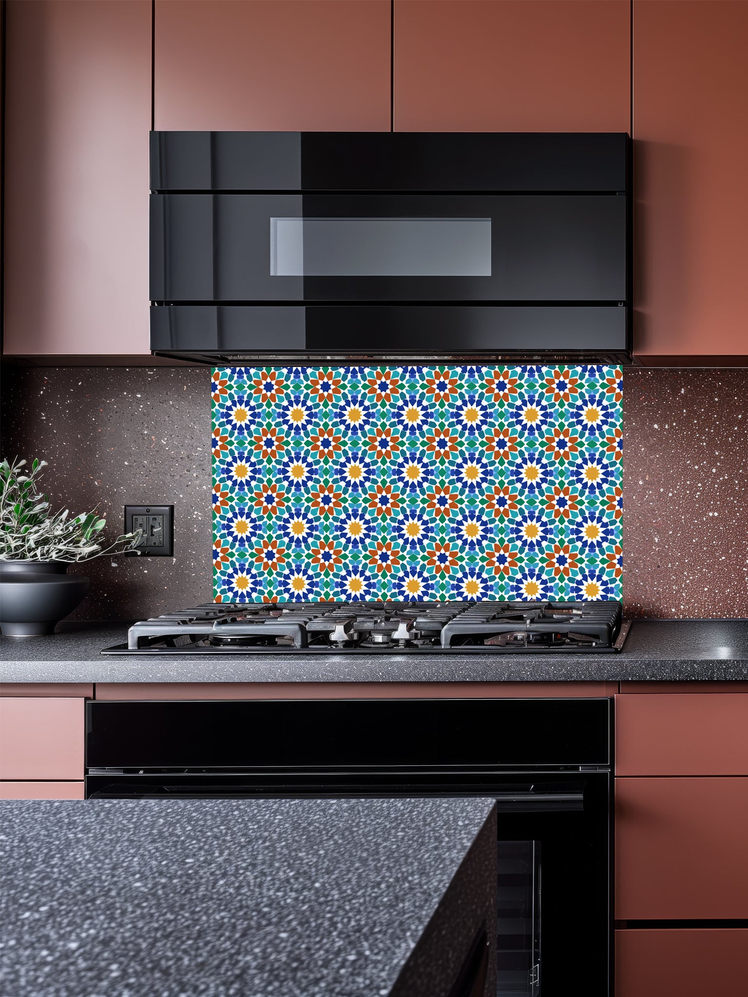 A stylish kitchen featuring a tempered glass backsplash with a vibrant Andalusian 8-pointed star geometric pattern in blue, green, and terracotta, installed behind a modern black stove.
