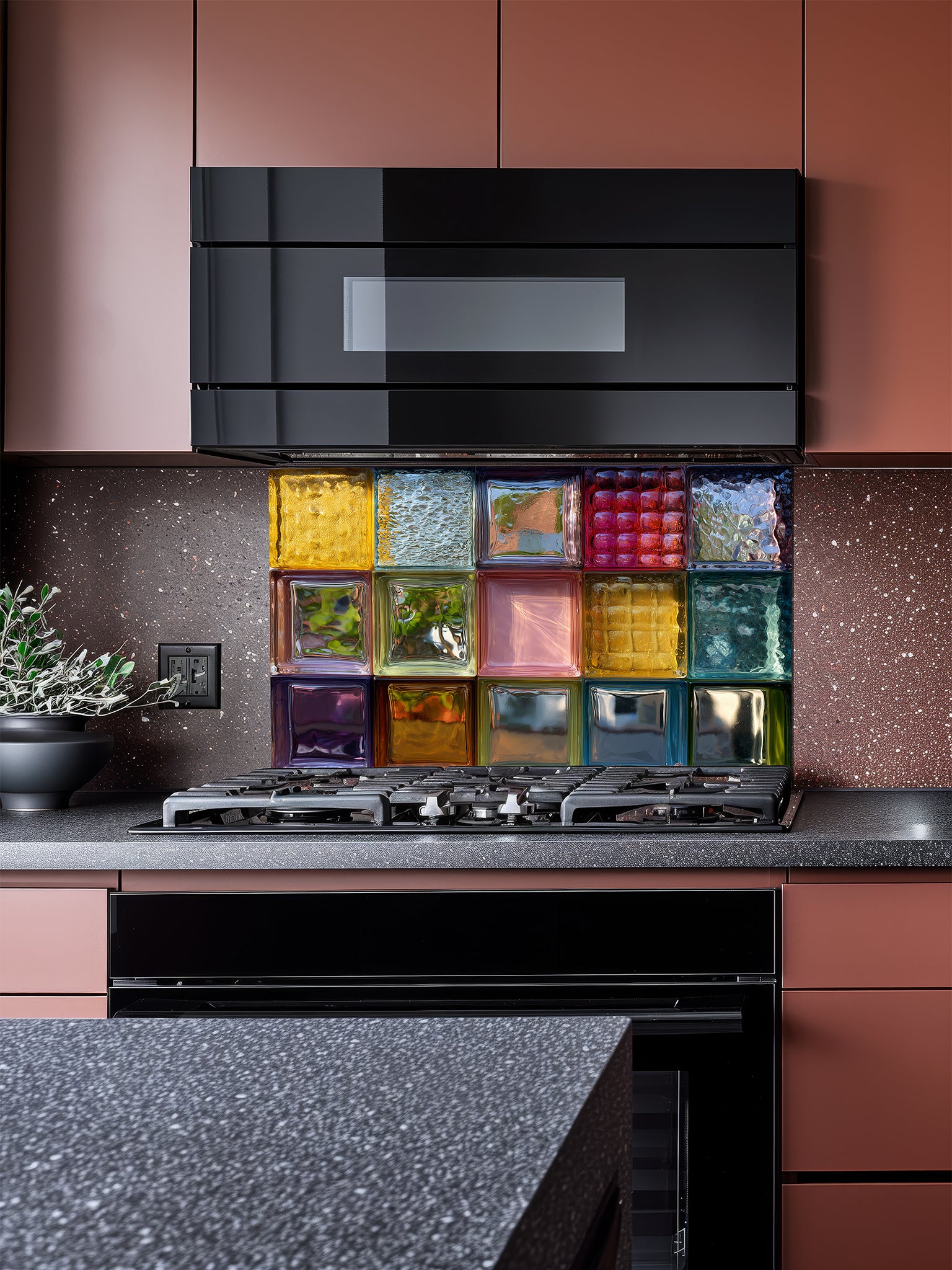 Tempered glass kitchen backsplash featuring a highly realistic 3D illusion of colorful, textured retro glass blocks in vibrant shades of blue, pink, amber, and green, installed behind a modern stainless steel stove.