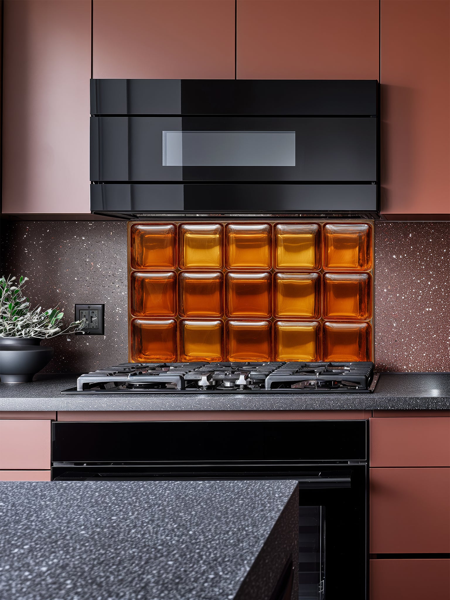 Tempered glass kitchen backsplash featuring a highly realistic 3D illusion of textured retro glass blocks in glowing, warm shades of amber and honey gold, installed behind a modern stainless steel stove.