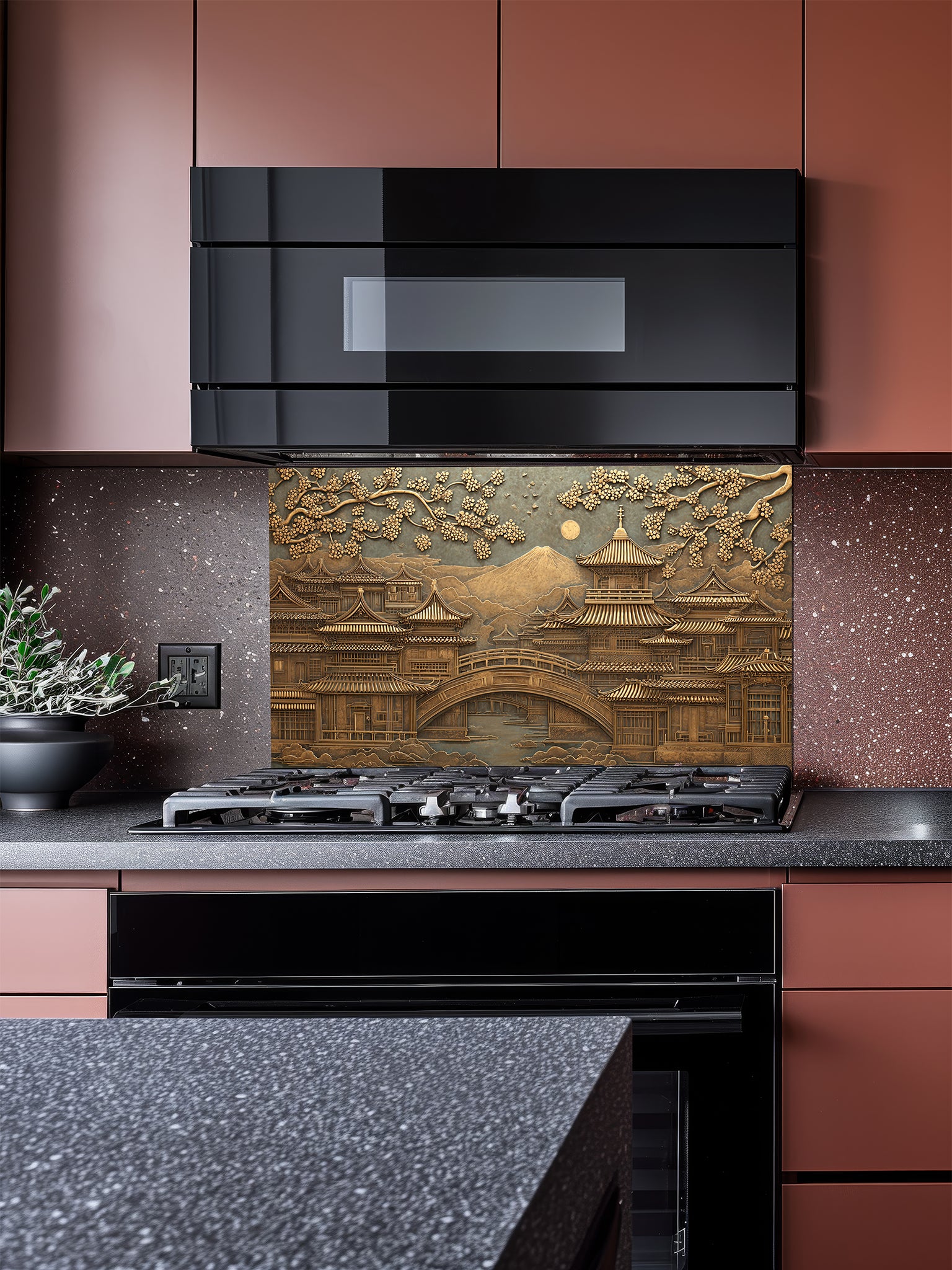 Tempered glass kitchen backsplash featuring a highly realistic 3D faux metal relief of a serene Japanese landscape with a traditional pagoda, bridge, cherry blossom trees, and a distant mountain in antique bronze tones, installed behind a modern stainless steel stove.