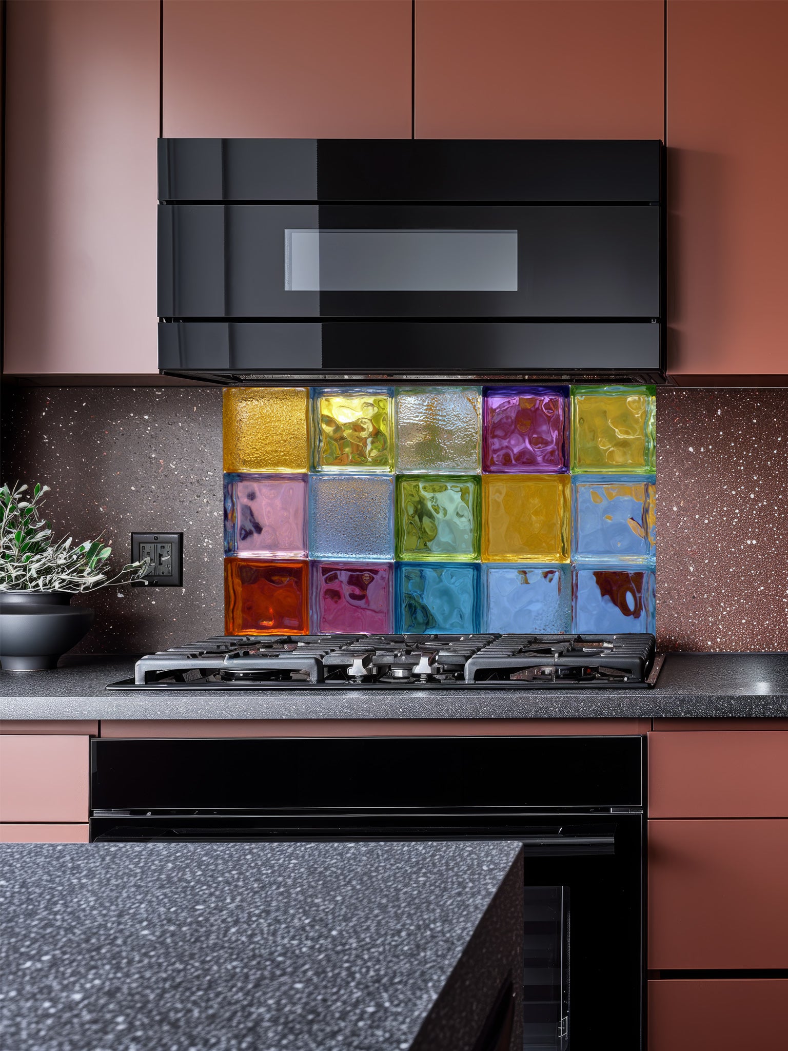 Tempered glass kitchen backsplash featuring a highly realistic 3D illusion of colorful architectural glass blocks in vibrant translucent hues of blue, green, yellow, and purple with wavy textures, installed behind a modern stainless steel stove.