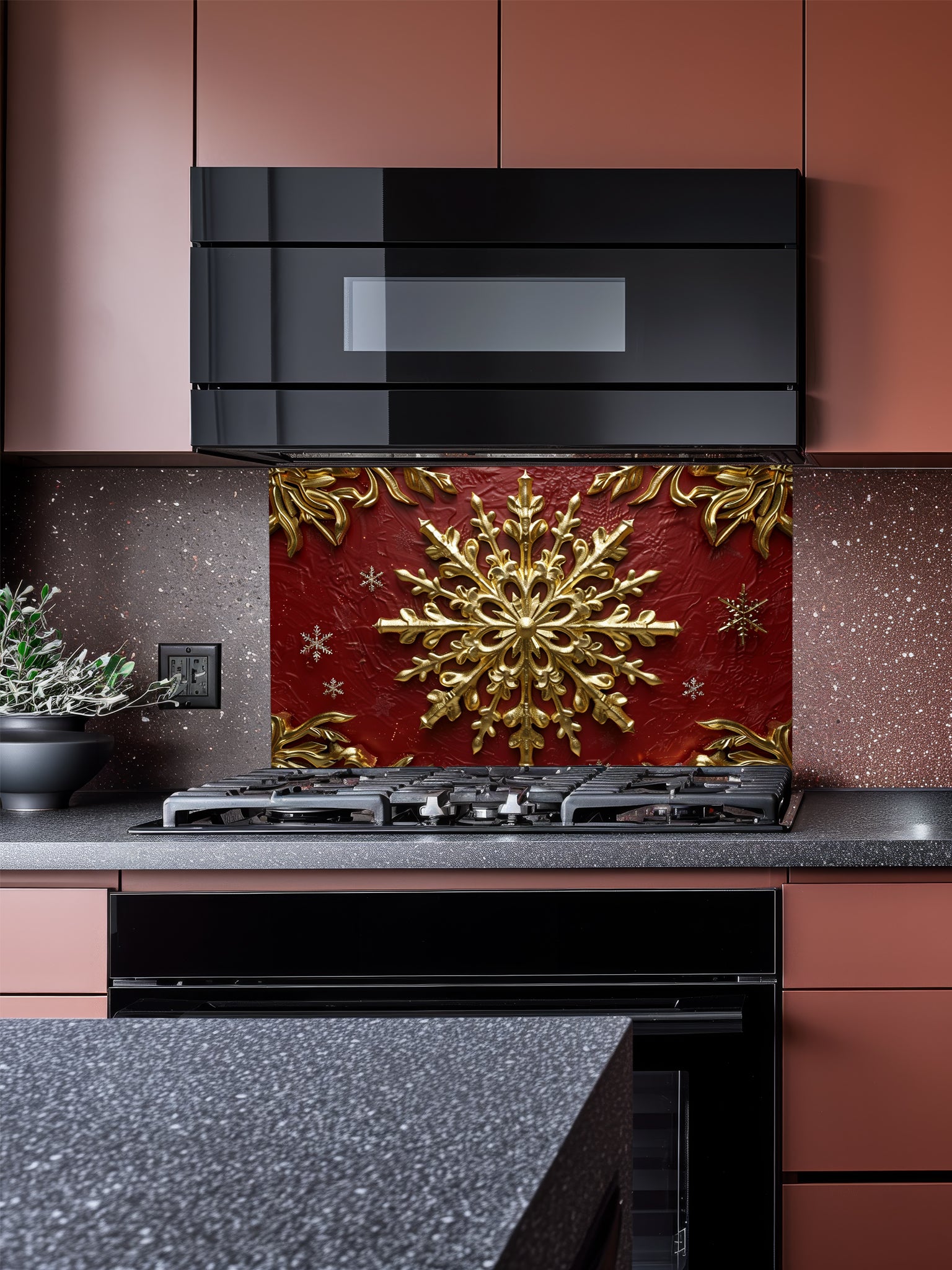 Tempered glass kitchen backsplash featuring a highly realistic 3D illusion of an ornate, embossed gold snowflake surrounded by smaller snowflakes and elegant golden corner flourishes against a rich, textured burgundy red background, installed behind a modern black stove.