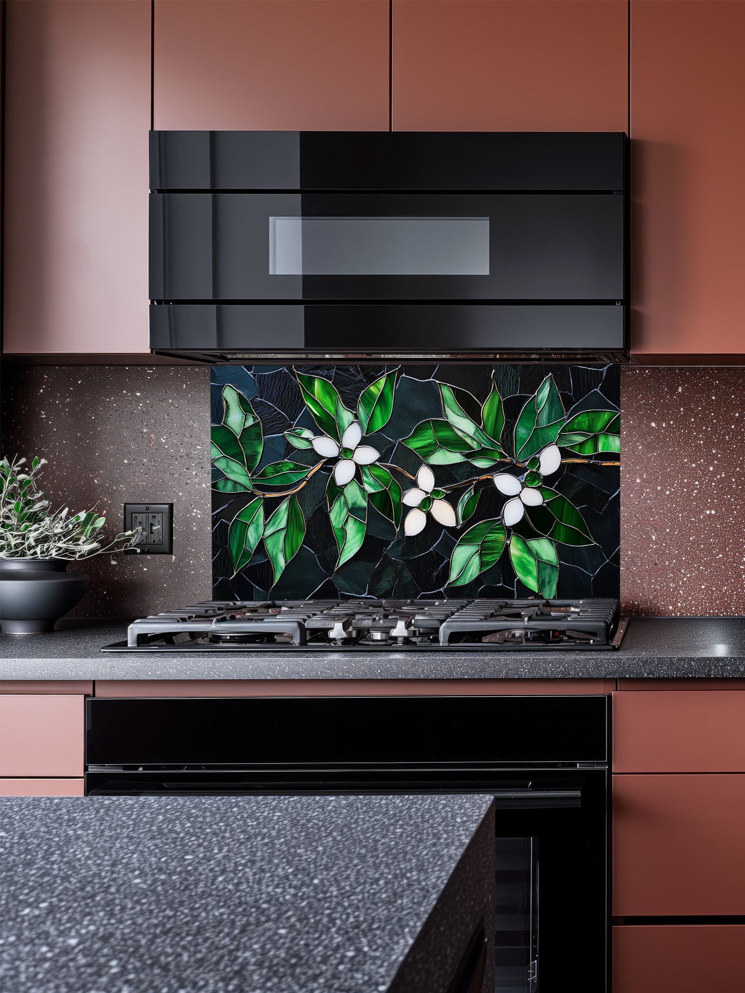Tempered glass kitchen backsplash featuring a highly realistic 3D illusion of stained glass and cracked mosaic art showing delicate white blossoms and vibrant emerald green leaves gracefully sprawling across a dark, moody charcoal and black background, installed behind a modern black stove.