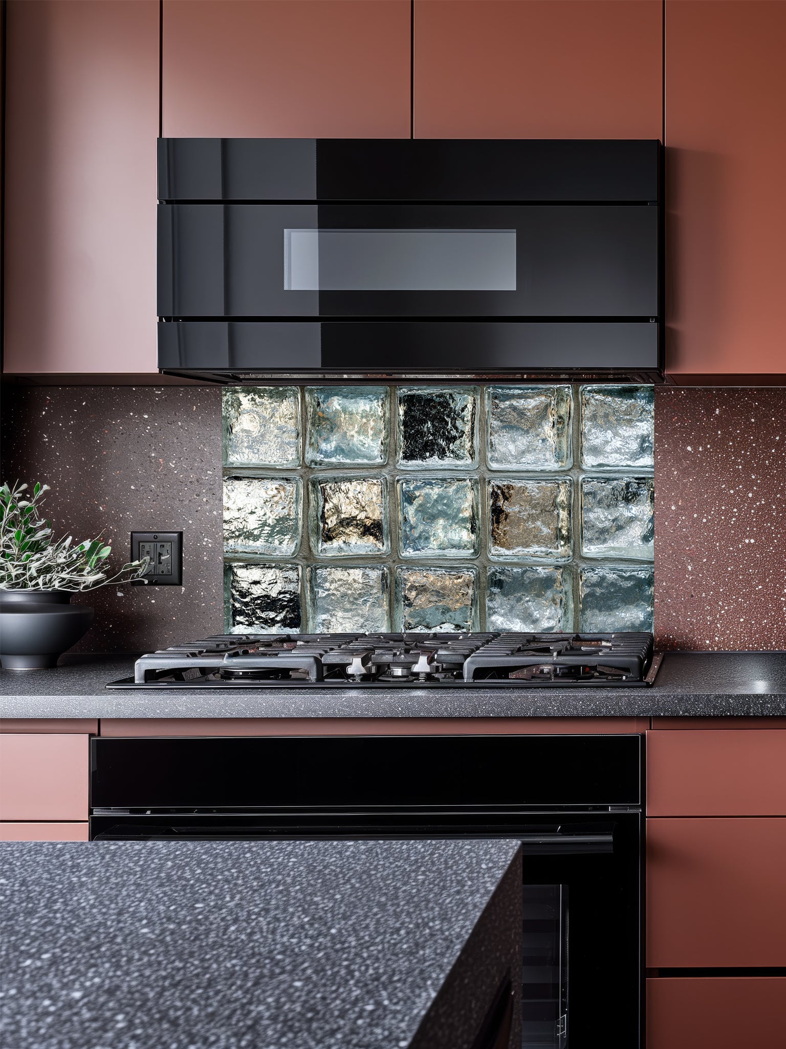 Tempered glass kitchen backsplash featuring a highly realistic 3D illusion of classic architectural clear glass blocks with authentic wavy, ice-like textures and sleek silver-grey reflections, installed behind a modern black stove.