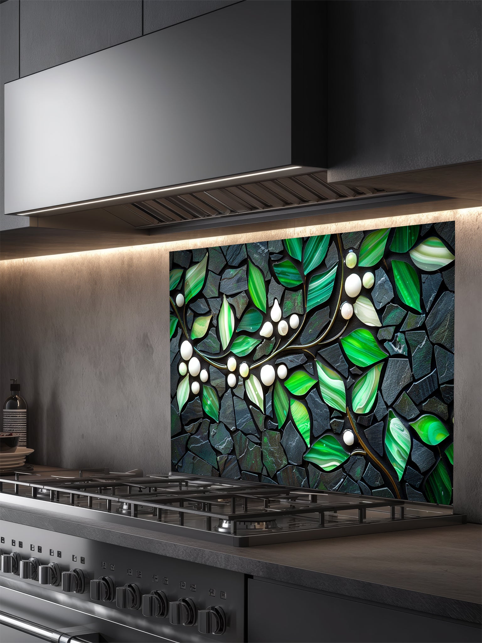 Tempered glass kitchen backsplash featuring a highly realistic 3D illusion of a stone mosaic showcasing vibrant emerald green agate-like leaves and white pearl berries on a glowing golden branch against a dark charcoal stone background, installed behind a modern black stove.
