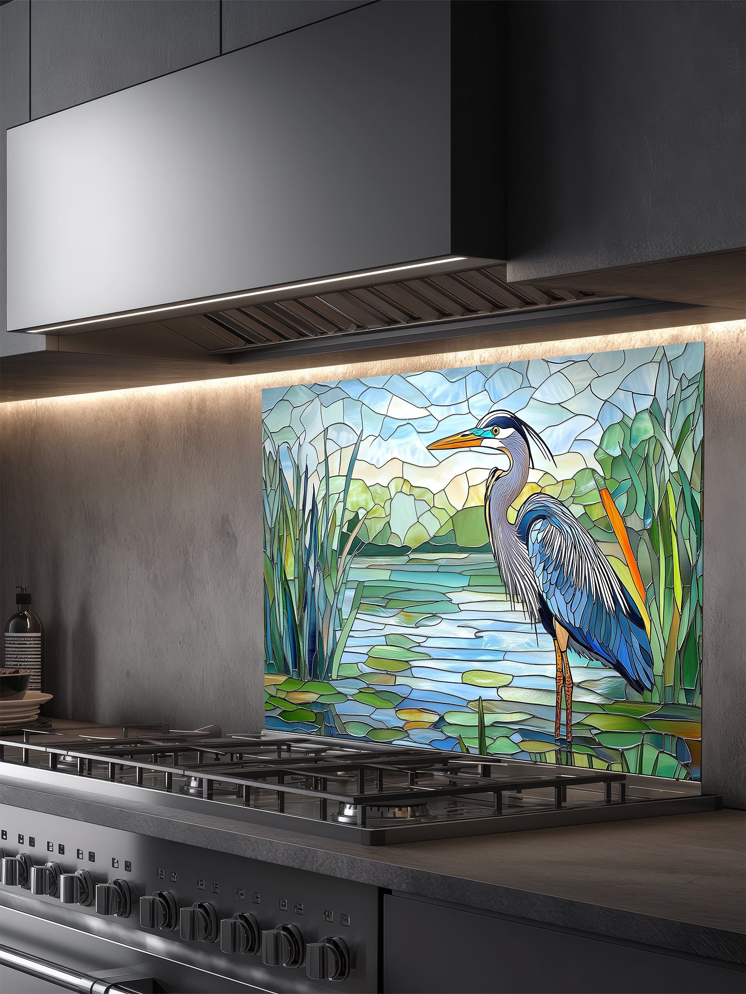 Tempered glass kitchen backsplash featuring a bright faux stained glass design of a majestic blue heron standing among lily pads against a clear blue sky and tranquil wetland, installed behind a modern stainless steel stove.