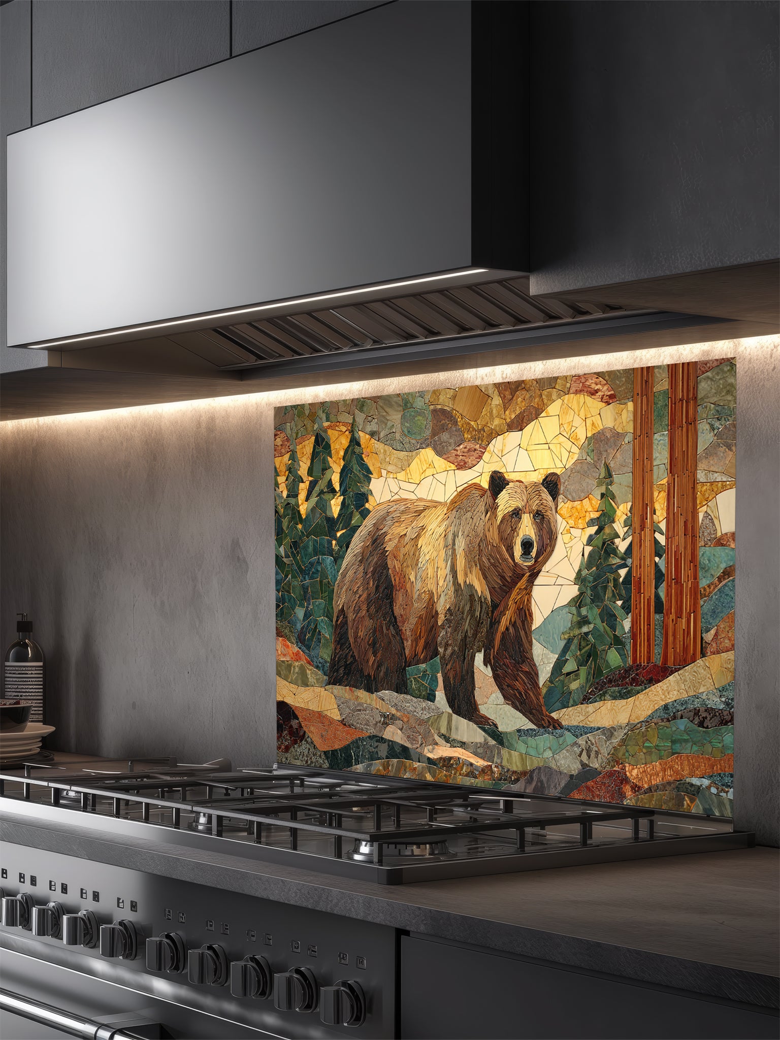 Tempered glass kitchen backsplash featuring a highly realistic 3D illusion of a rugged stone mosaic artwork showing a majestic brown bear walking through a forest of pine trees and mountains in earthy brown, green, and golden tones, installed behind a modern black stove.