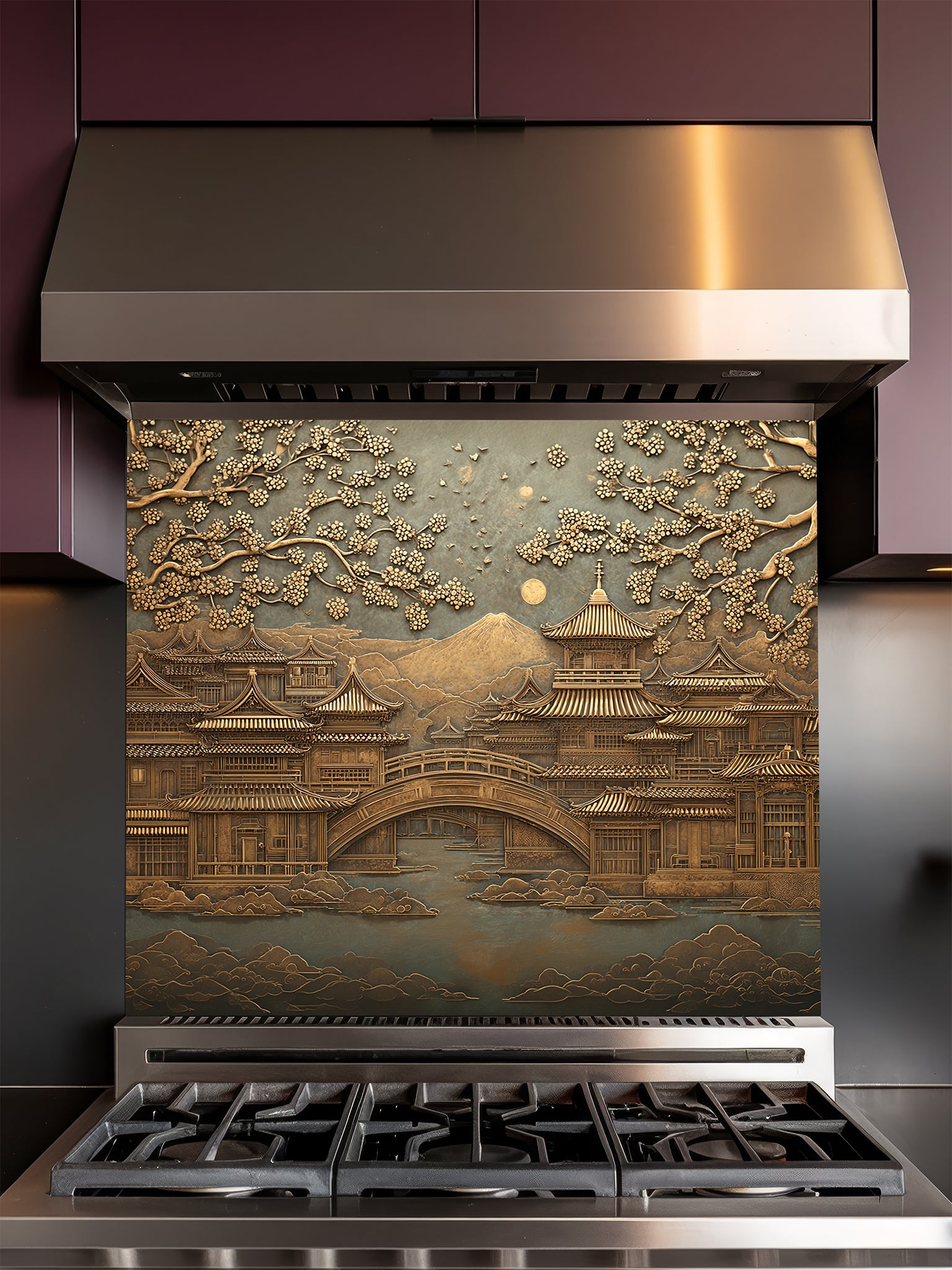 Tempered glass kitchen backsplash featuring a highly realistic 3D faux metal relief of a serene Japanese landscape with a traditional pagoda, bridge, cherry blossom trees, and a distant mountain in antique bronze tones, installed behind a modern stainless steel stove.