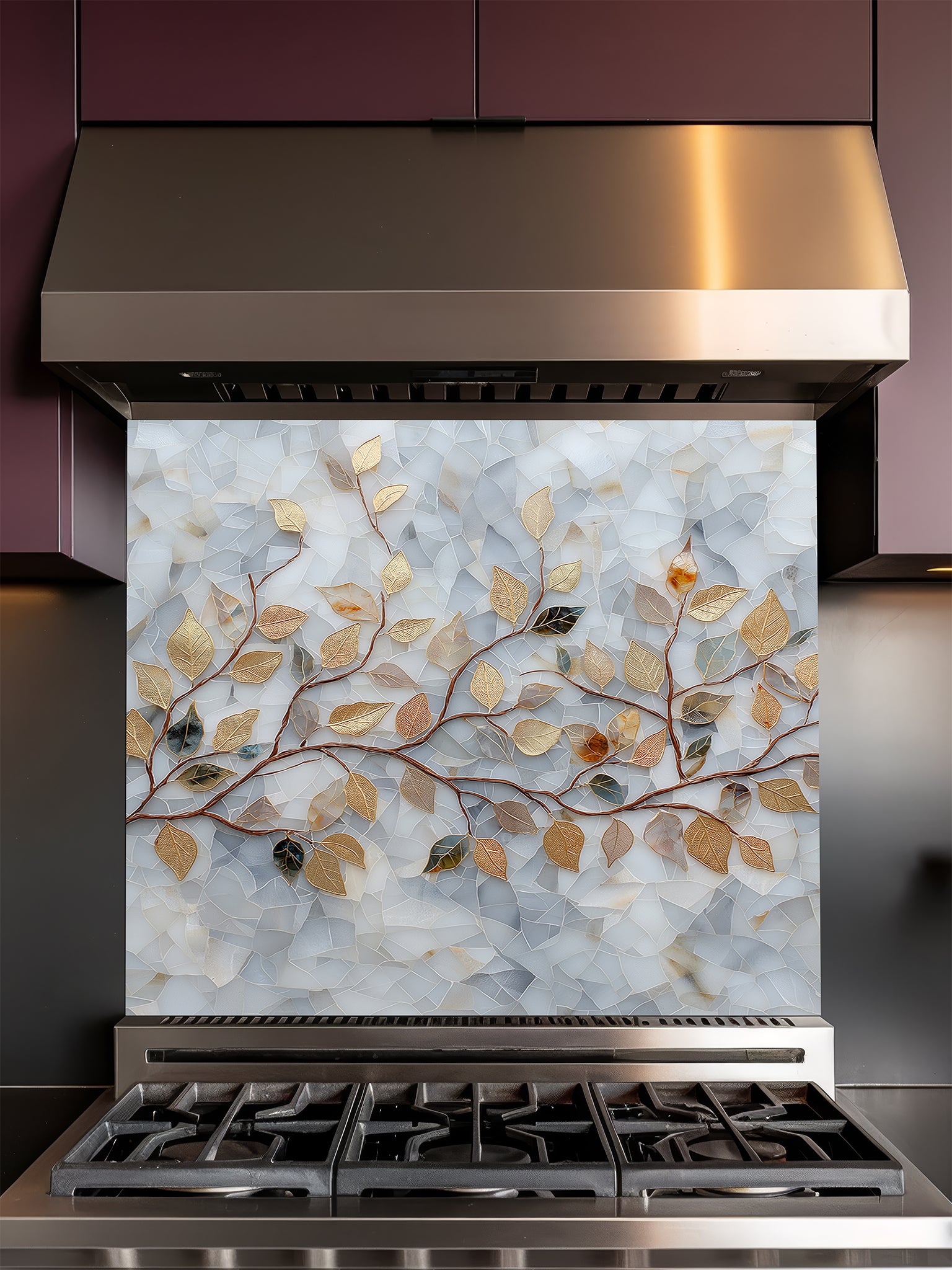 Tempered glass kitchen backsplash featuring a realistic 3D-effect design of elegant gold and bronze leaves on curving branches over a pearlescent white and soft grey cracked mosaic background, installed behind a modern stainless steel stove.
