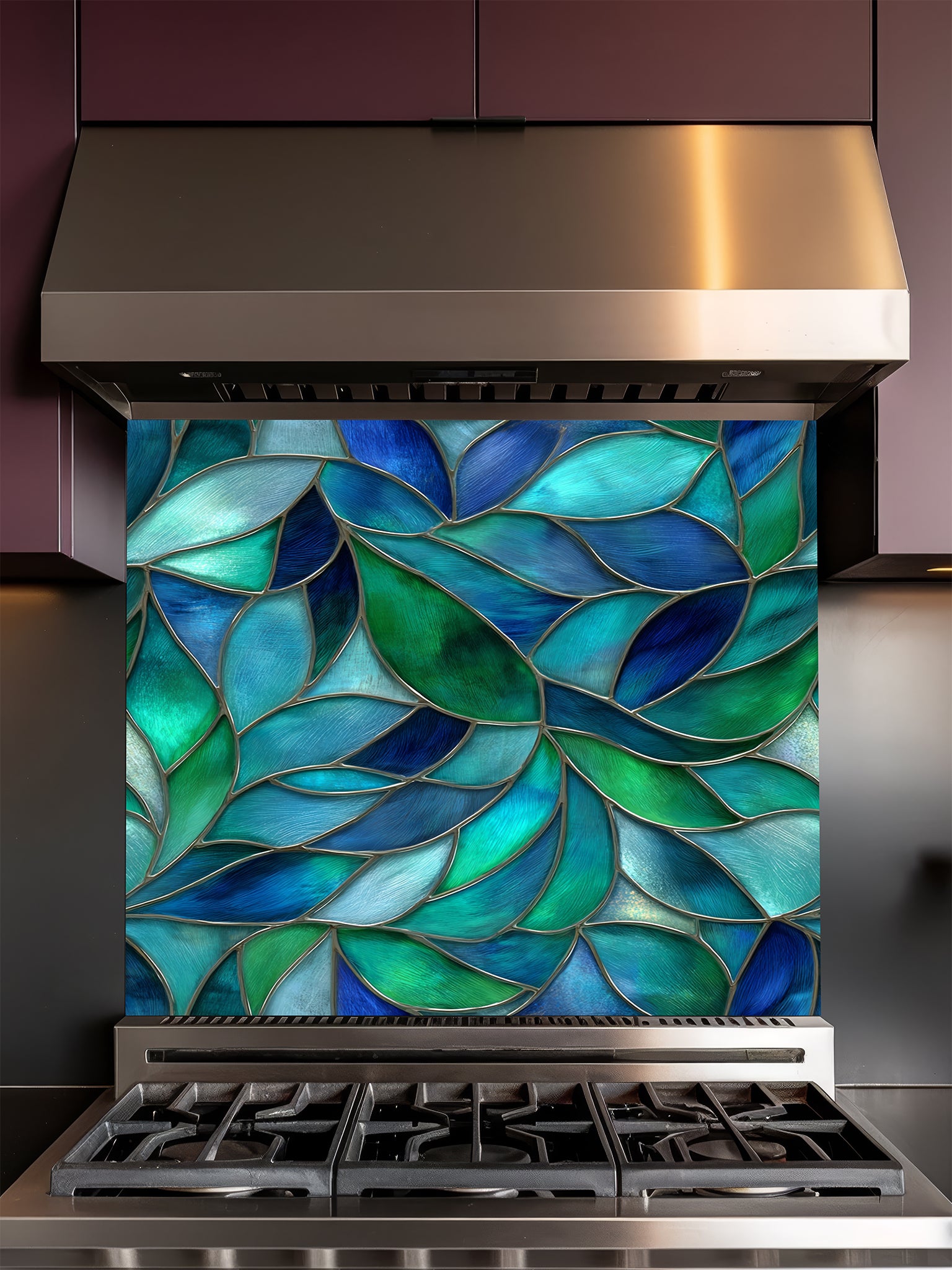 Tempered glass kitchen backsplash featuring a vibrant botanical stained glass effect with overlapping leaves in shades of teal, blue, and emerald green, installed behind a modern stainless steel stove.