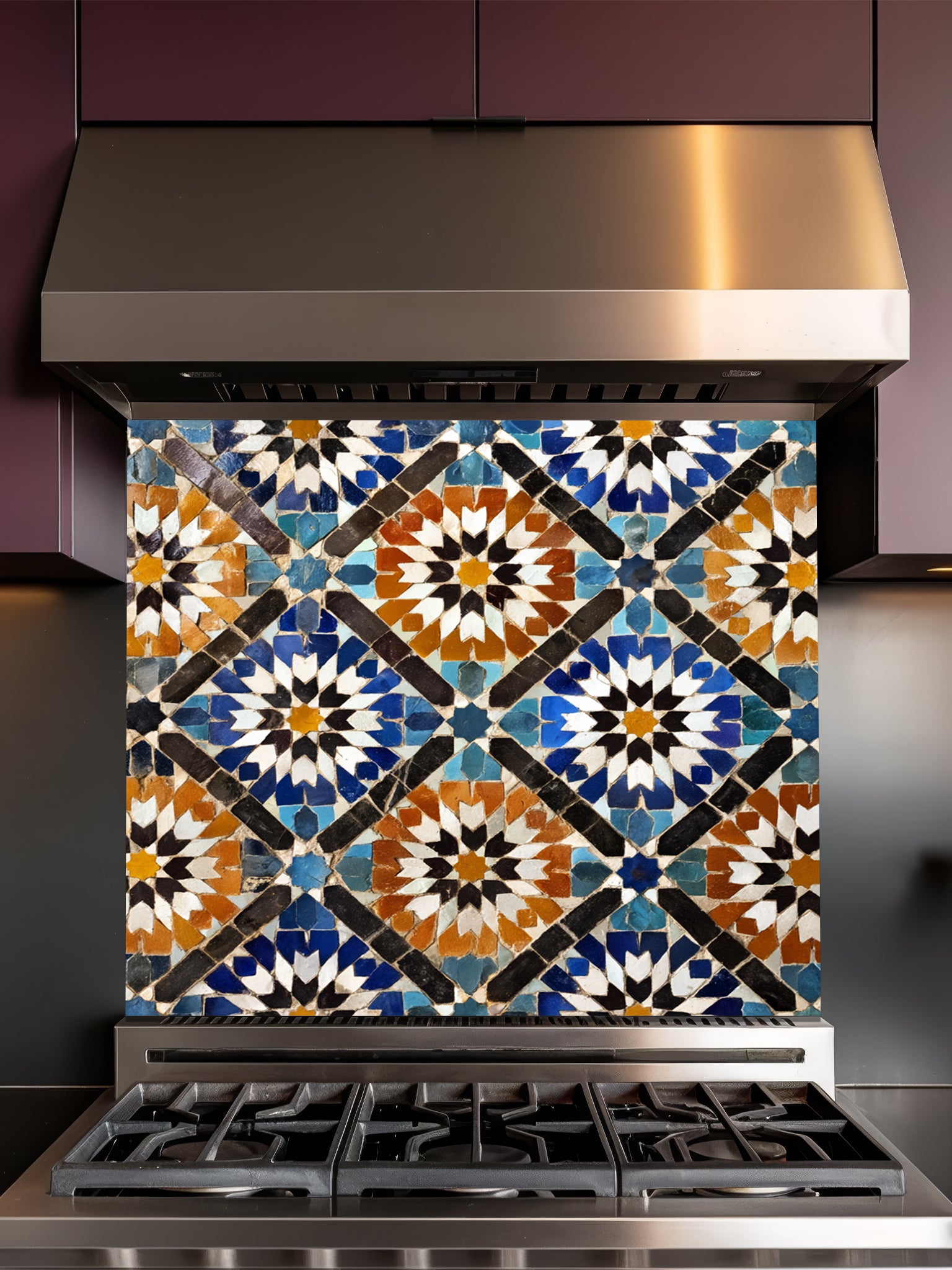 Stainless steel range hood with a decorative mosaic tile panel on a dark background
