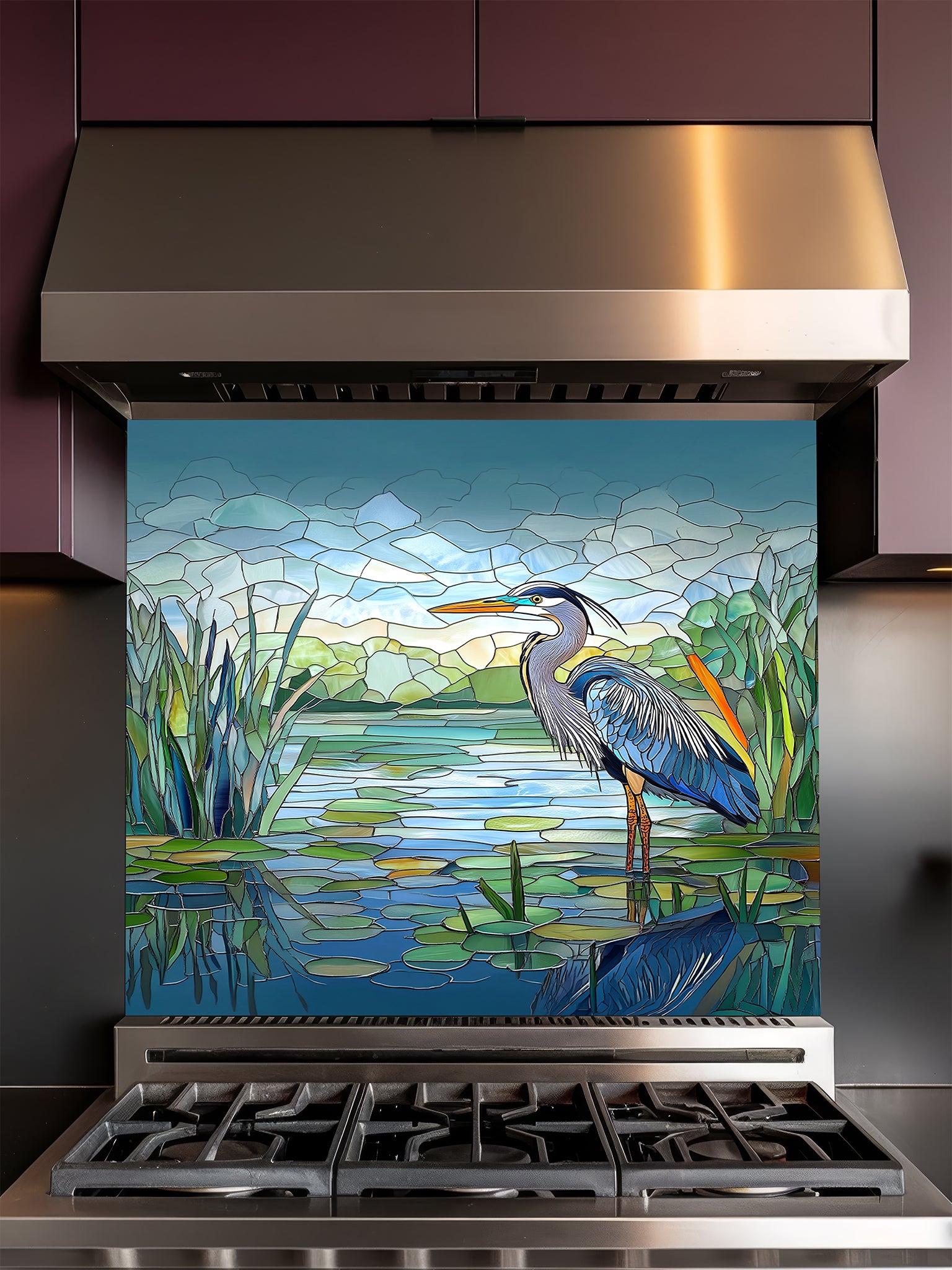 Tempered glass kitchen backsplash featuring a bright faux stained glass design of a majestic blue heron standing among lily pads against a clear blue sky and tranquil wetland, installed behind a modern stainless steel stove.