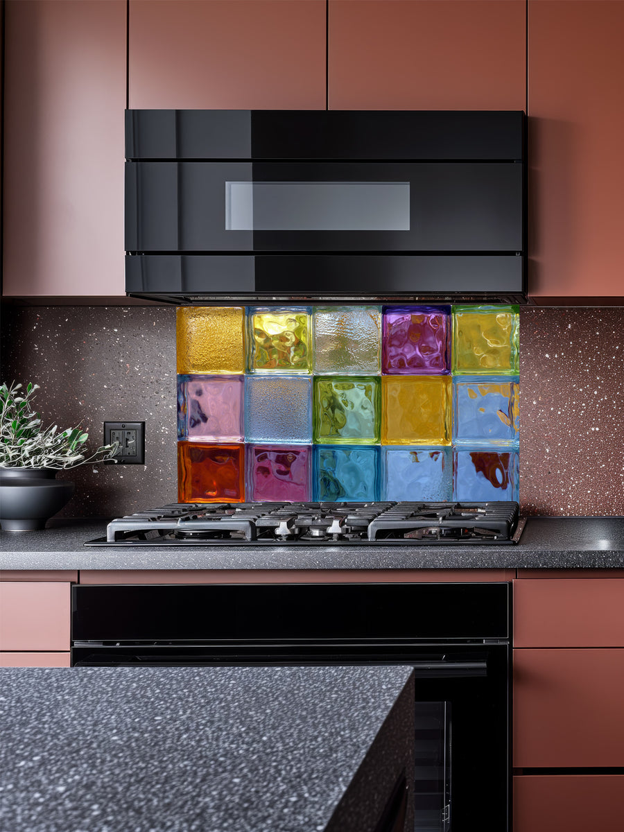 Tempered glass kitchen backsplash featuring a highly realistic 3D illusion of colorful architectural glass blocks in vibrant translucent hues of blue, green, yellow, and purple with wavy textures, installed behind a modern stainless steel stove.