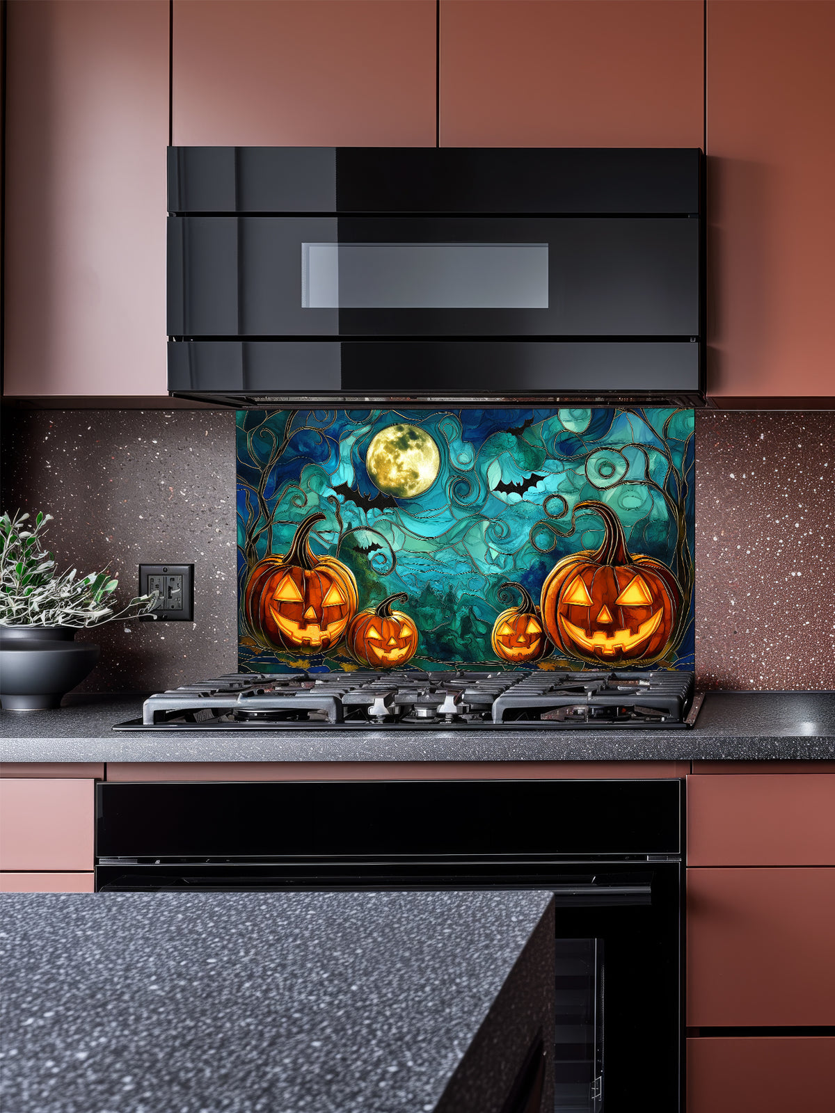 A festive kitchen featuring a tempered glass backsplash with a spooky stained glass effect illustration showing glowing Halloween pumpkins, bats, and a full moon, installed behind a black stove.