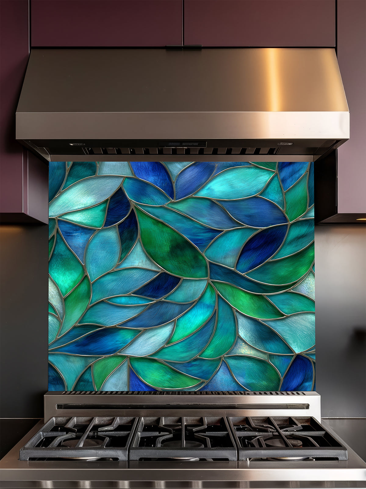 Tempered glass kitchen backsplash featuring a vibrant botanical stained glass effect with overlapping leaves in shades of teal, blue, and emerald green, installed behind a modern stainless steel stove.