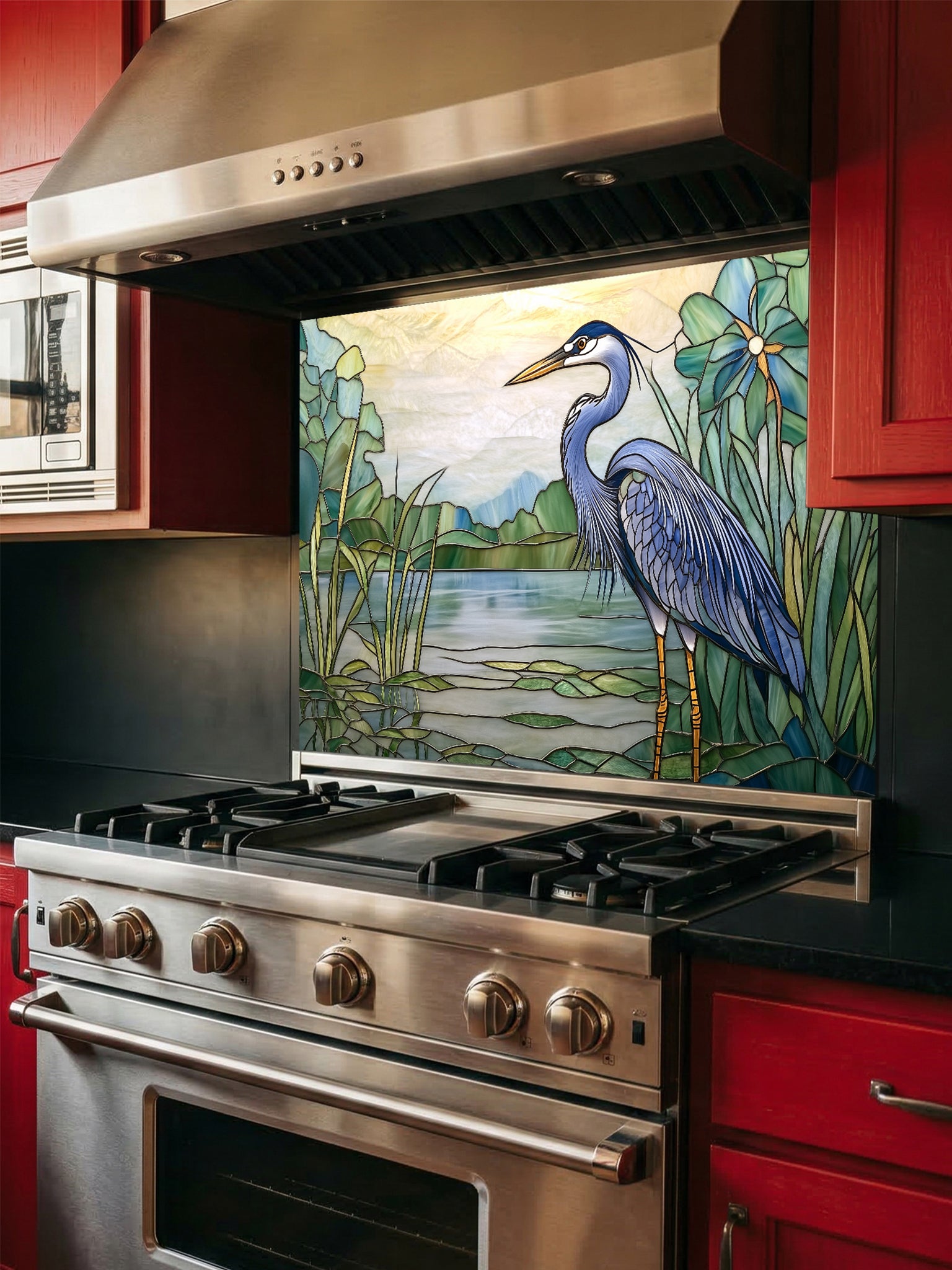 Tempered glass kitchen backsplash featuring a bright faux stained glass design of a majestic blue heron standing among lily pads against a glowing sunrise and mountain landscape, installed behind a modern stainless steel stove.